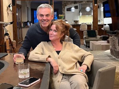 Ann Cowherd is sitting as Colin Cowherd is standing behind her in the picture.